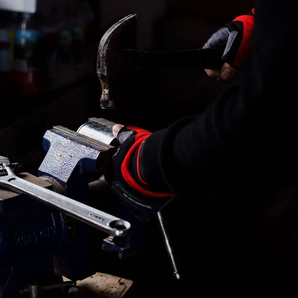 Gloved technician tightening a pipe fitting with a wrench