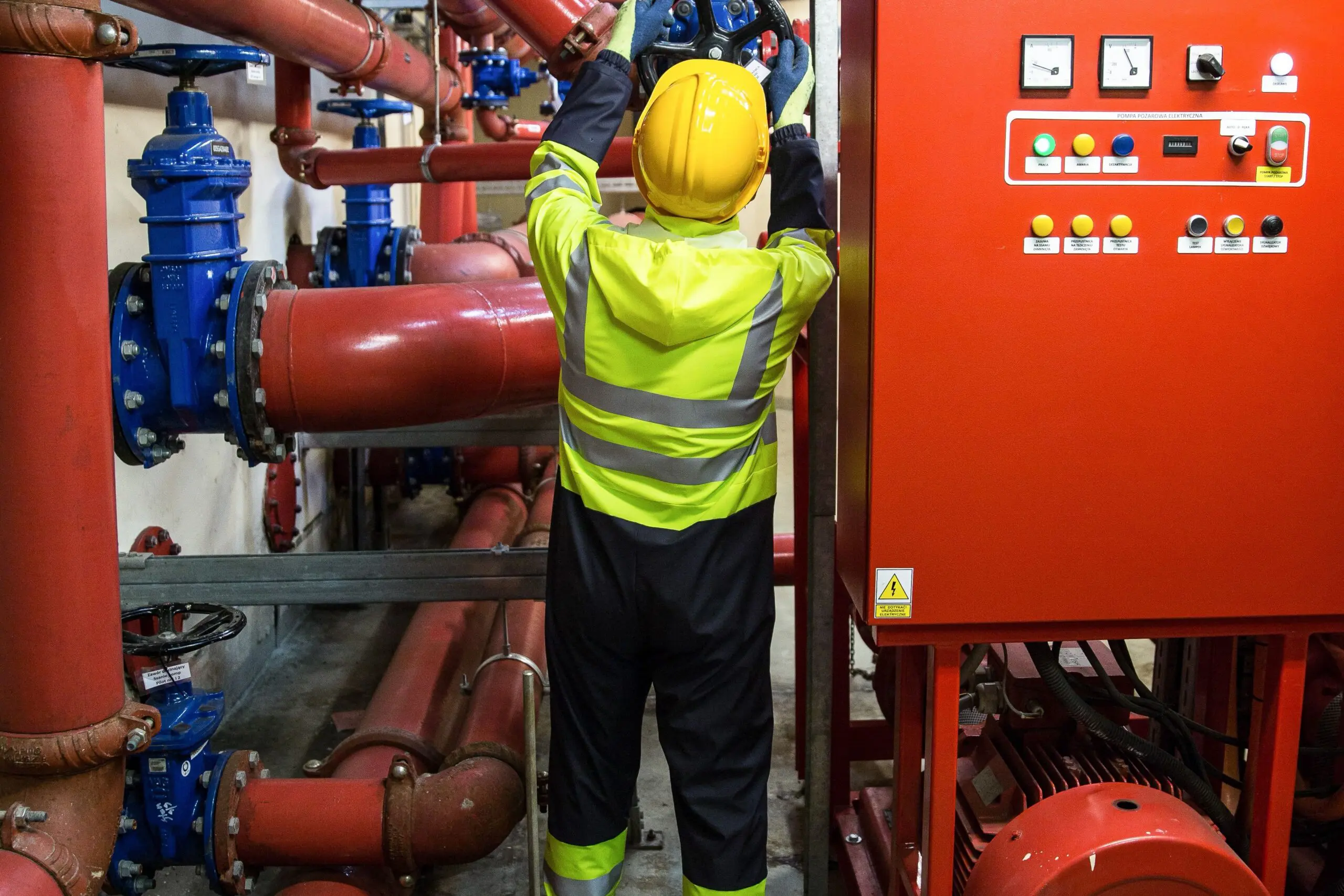 Fire suppression technician in hi vis gear turning a valve wheel on a fire pump